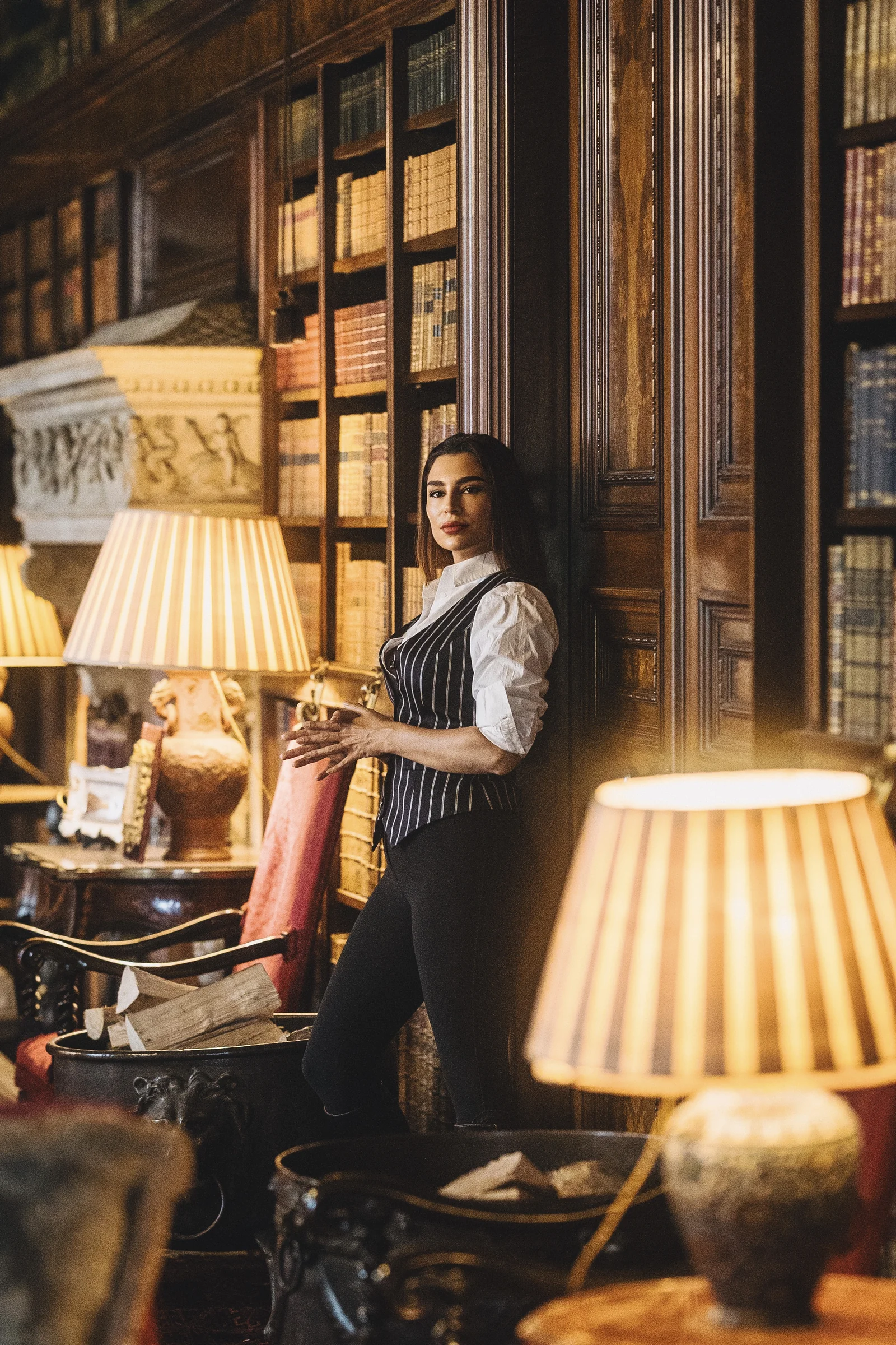 Handan Darici in a pinstripe waistcoat among the shelves of a lamplit library